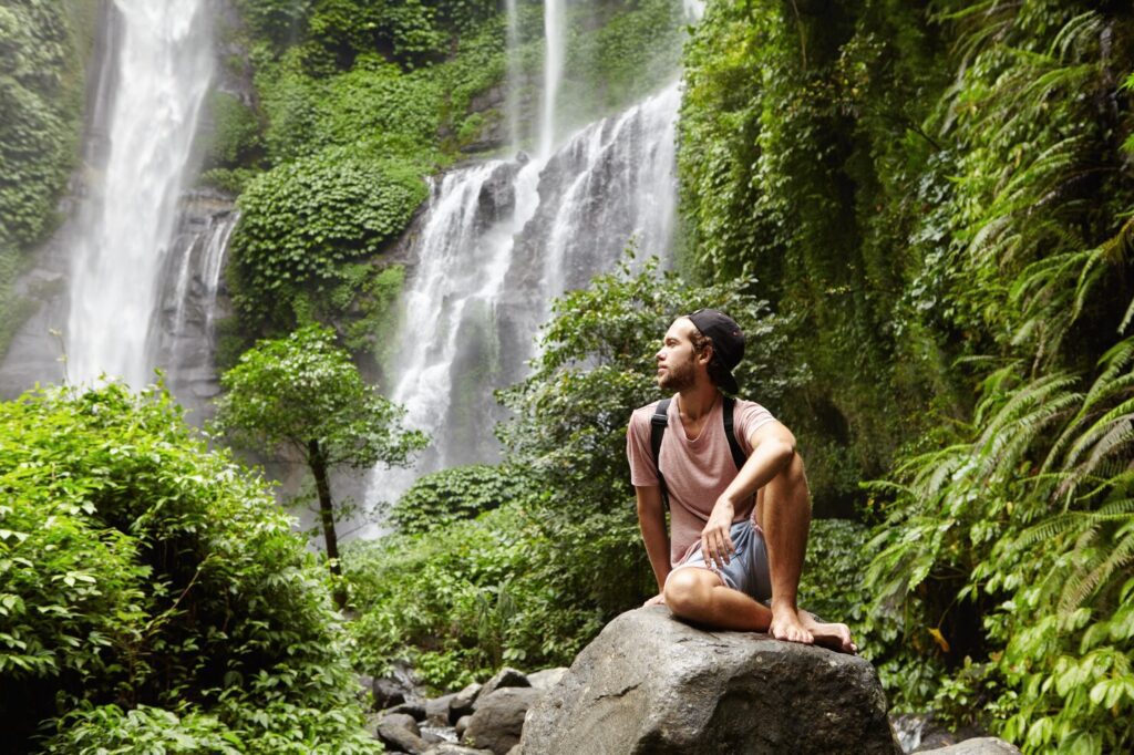 natureza turismo e pessoas jovem turista descalca vestindo jeans curta e mochila sentado na pedra grande profundamente dentro da floresta verde 273609 1610